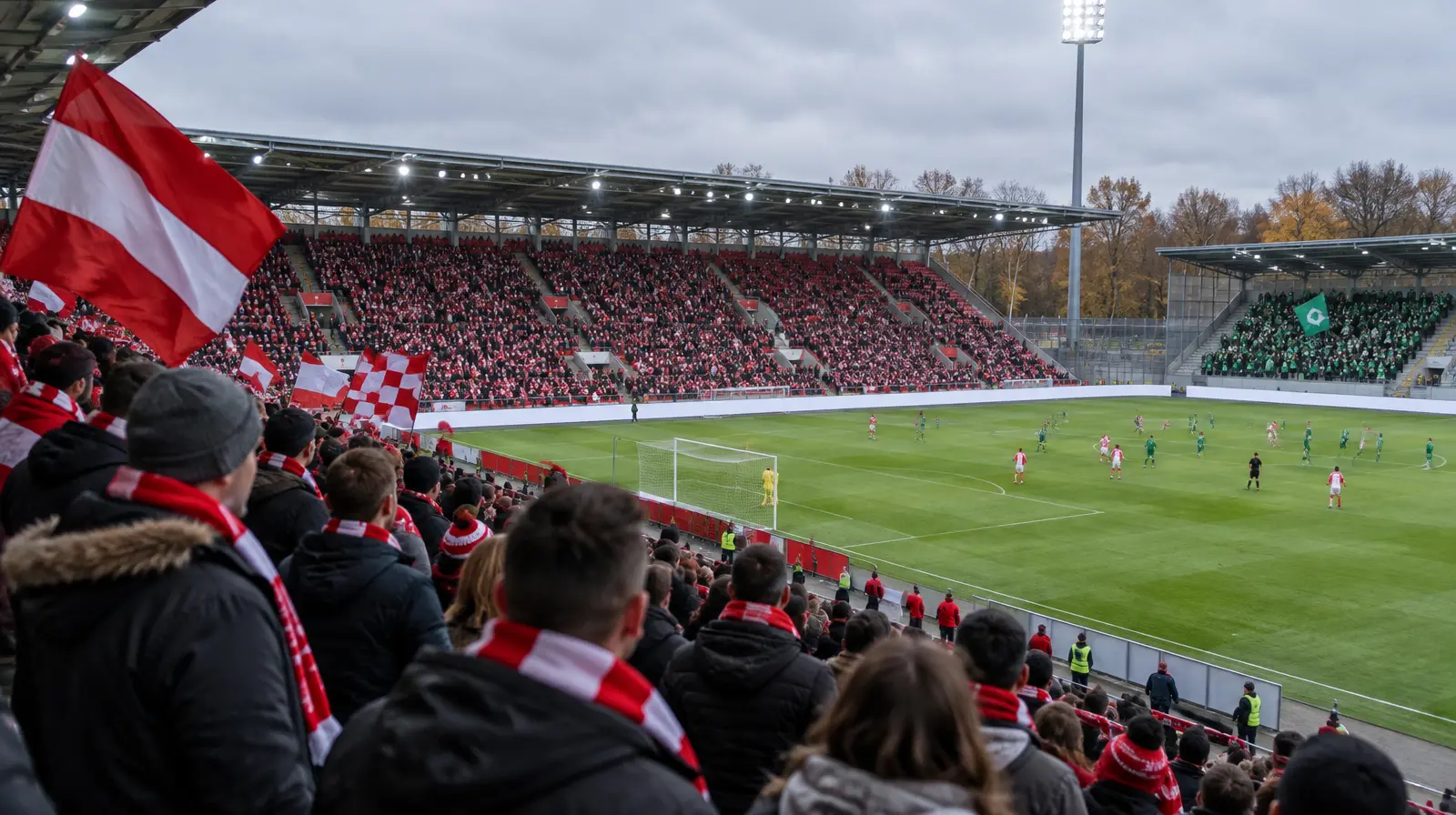 Hemmasupportrar i rött och vitt följer matchen från läktaren en höstdag.